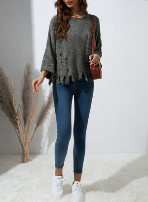 Distressed knit sweater in dark gray with frayed hem and details.