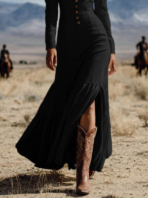 Black long sleeve maxi dress with button detail and high slit, styled with cowboy boots.