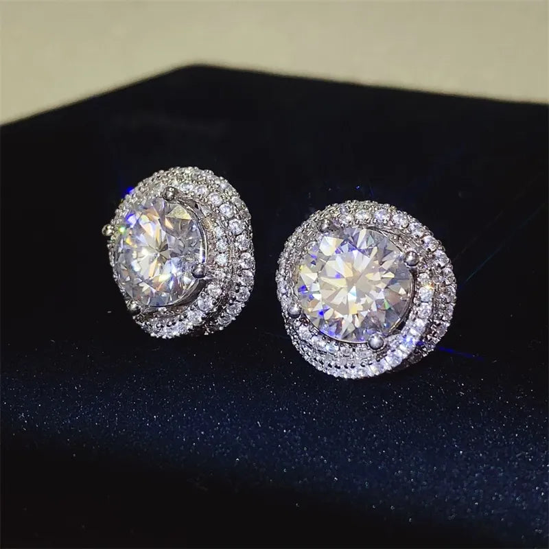 Halo diamond cluster stud earrings in silver with a central round-cut stone surrounded by smaller stones.