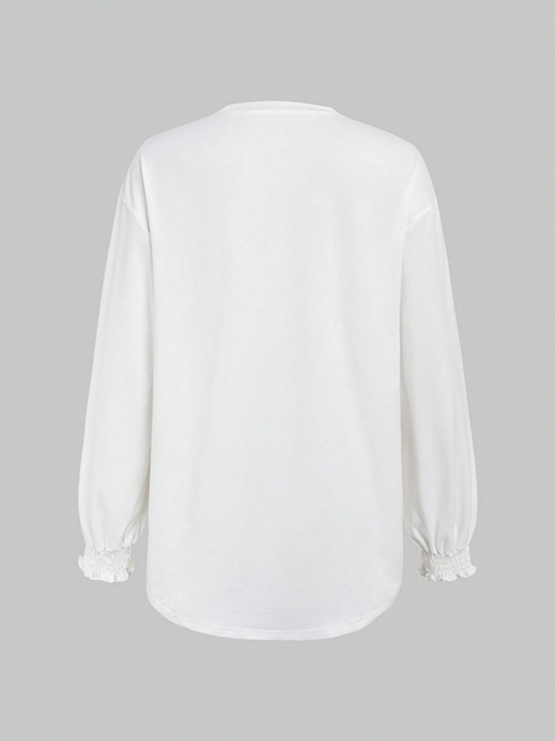 White oversized tunic top with ruffled cuffs and long sleeves.