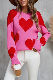 Pink and red heart patchwork knit sweater with crew neck and long sleeves.