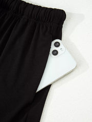 Black pajama pants with elastic waist and side pocket holding a smartphone.