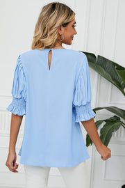 Light blue blouse with pleated sleeves and smocked cuffs, featuring a keyhole back detail.