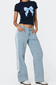 Light blue denim wide-leg trousers with white side stripes and tie detail at hem.