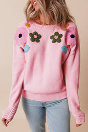 Pink knit sweater with embroidered floral appliqués and ribbed cuffs.