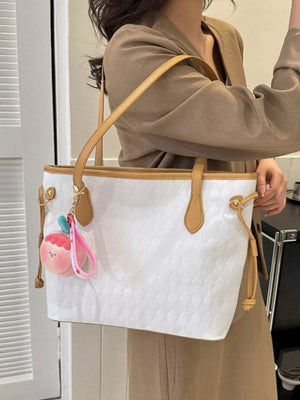 Textured diamond woven tote bag in white with tan trim and a fruit charm.