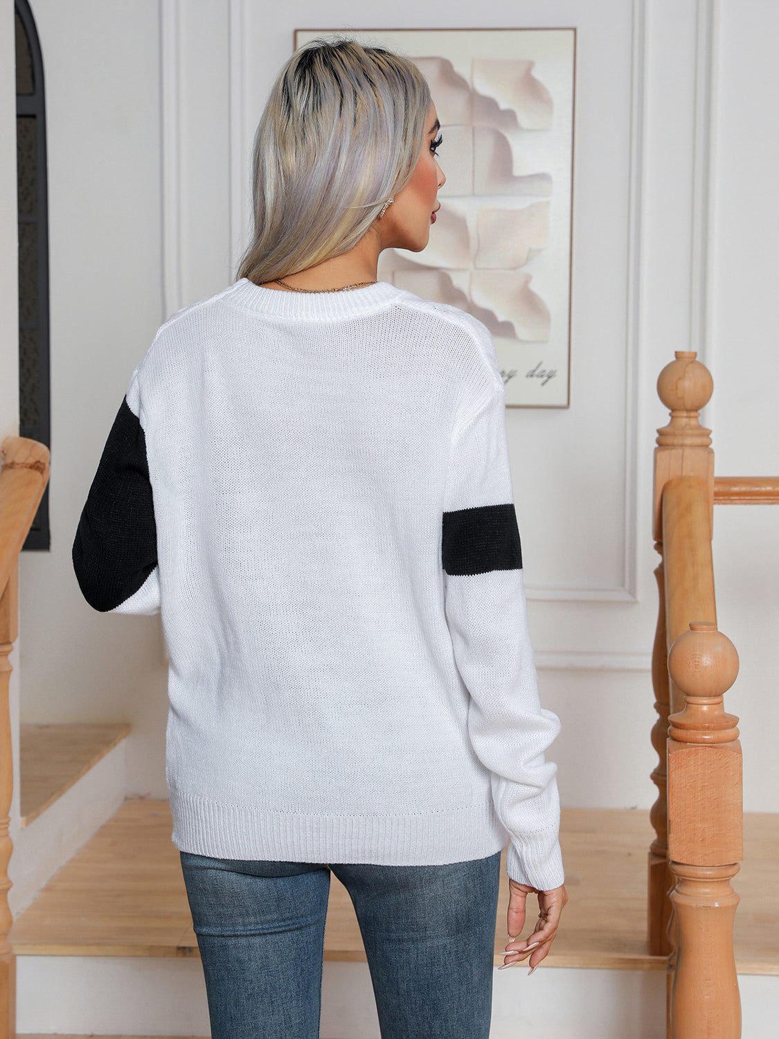 White acrylic cable knit crewneck sweater with black colorblock detail on sleeves.