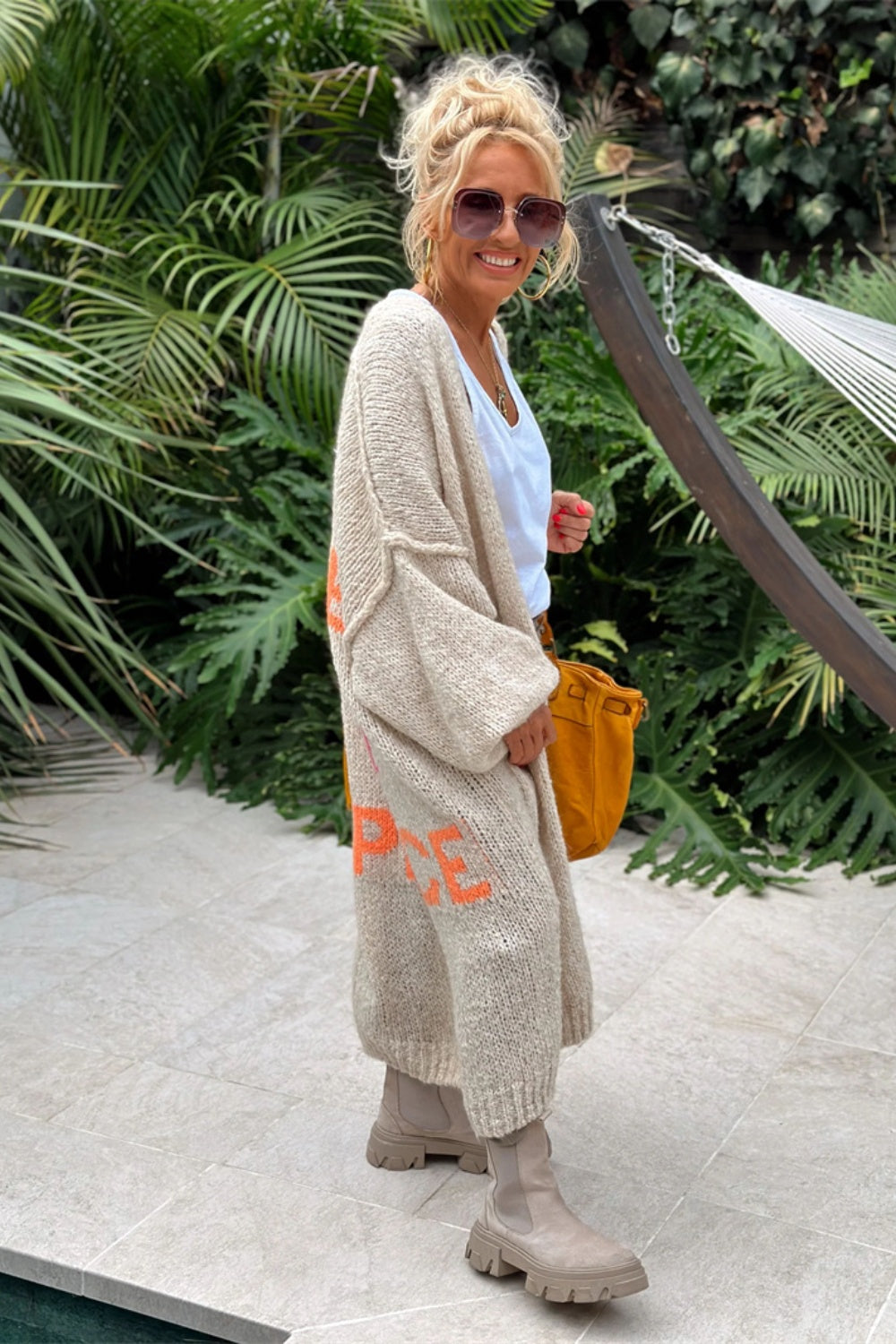 Long beige knit cardigan with orange peace sign detail, open front, long sleeves