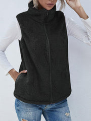 Black teddy fleece stand-collar vest with zipper and pockets, worn over a white long-sleeve shirt.