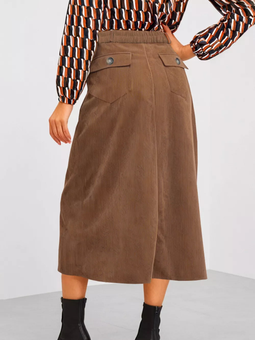 Brown corduroy midi skirt with buttoned flap pockets and elastic waistband.
