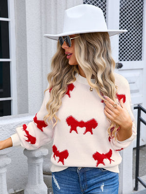 Cream knit pullover with red bow motif, crew neck, long sleeves, acrylic blend.