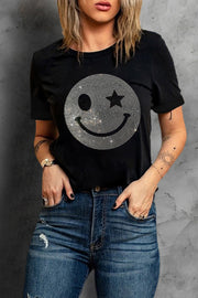 Black t-shirt with rhinestone smiley face graphic and star eye detail.