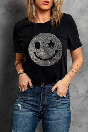 Black t-shirt with rhinestone smiley face graphic and star eye detail.
