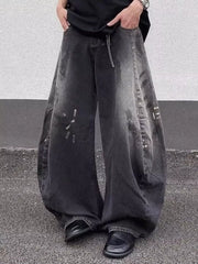 Men's black wide leg distressed jeans with a baggy fit and chain detail.
