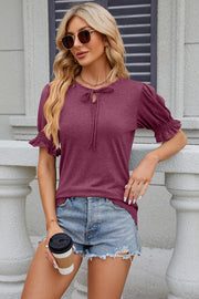 Red-violet tee with tie-neck, puffed short sleeves, and ruffled cuffs.
