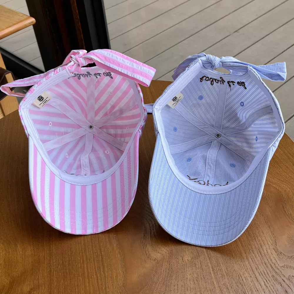 Pastel striped cotton baseball caps in pink and blue with bow detail.