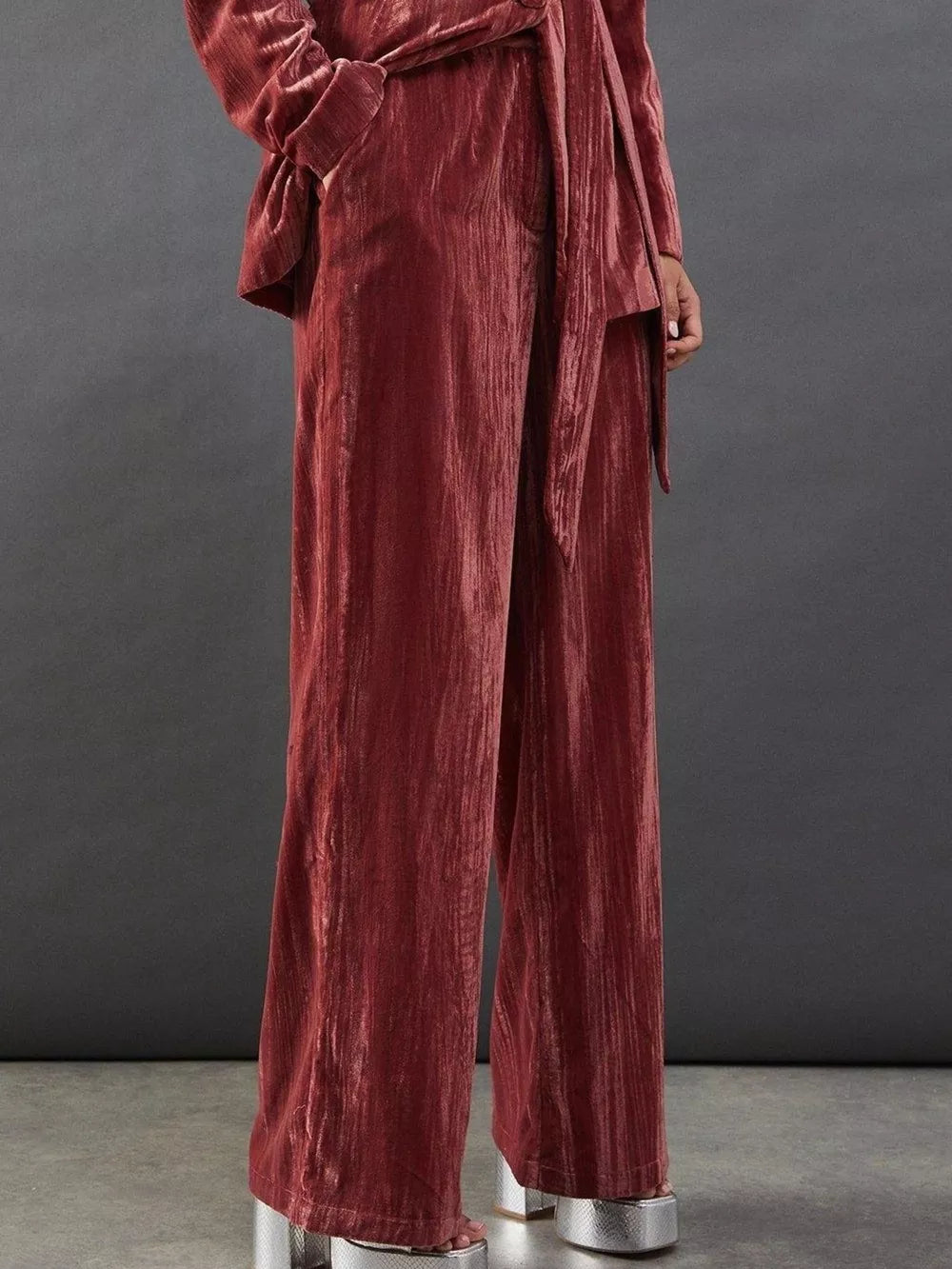 Burgundy velvet wide-leg pants and belted blazer ensemble with a tie detail.