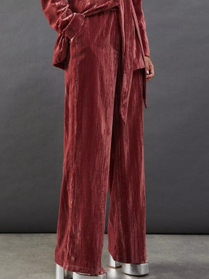 Burgundy velvet wide-leg pants and belted blazer ensemble with a tie detail.
