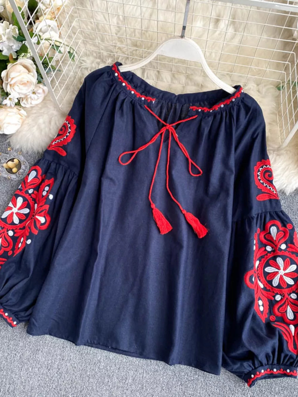 Navy blue peasant blouse with red embroidery, tie neck, and tassel details.