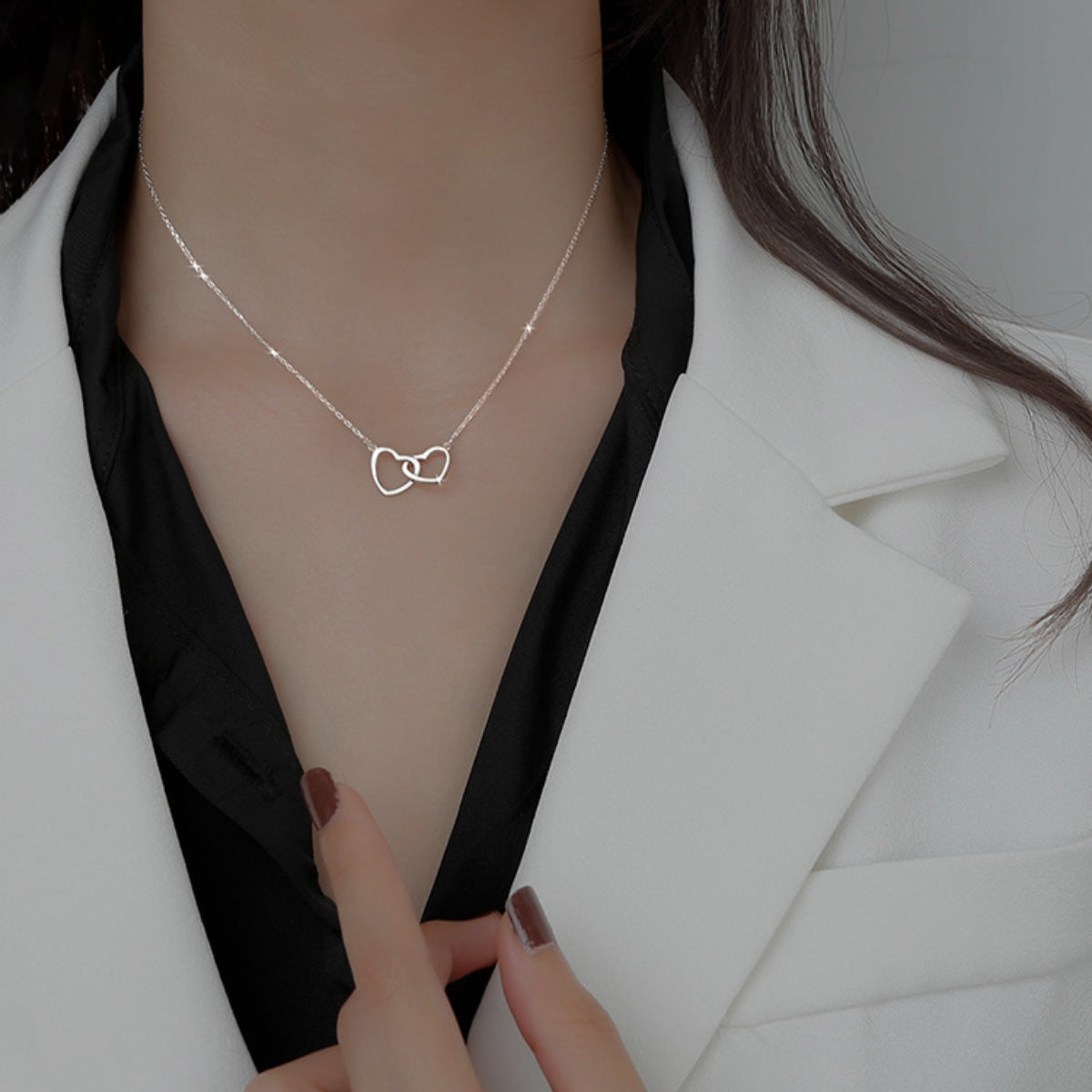 Silver interlocking heart pendant necklace with delicate chain.