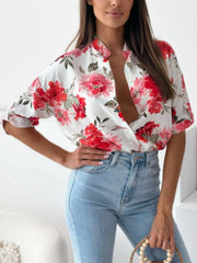 Floral print blouse with mandarin collar and button front, short sleeves, in white with red and pink flowers.