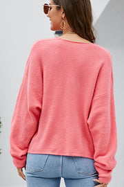 Watermelon pink textured knit pullover sweater with a deep V-neck and long sleeves.