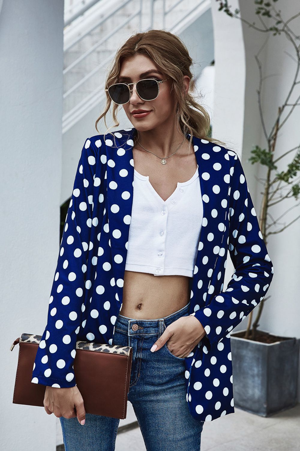 Dark blue polka dot open-front blazer with long sleeves, styled with a white crop top and jeans.