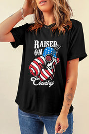 Black graphic t-shirt with American flag guitar and Raised On Country text