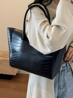 Black crocodile-embossed medium tote bag with top handles.