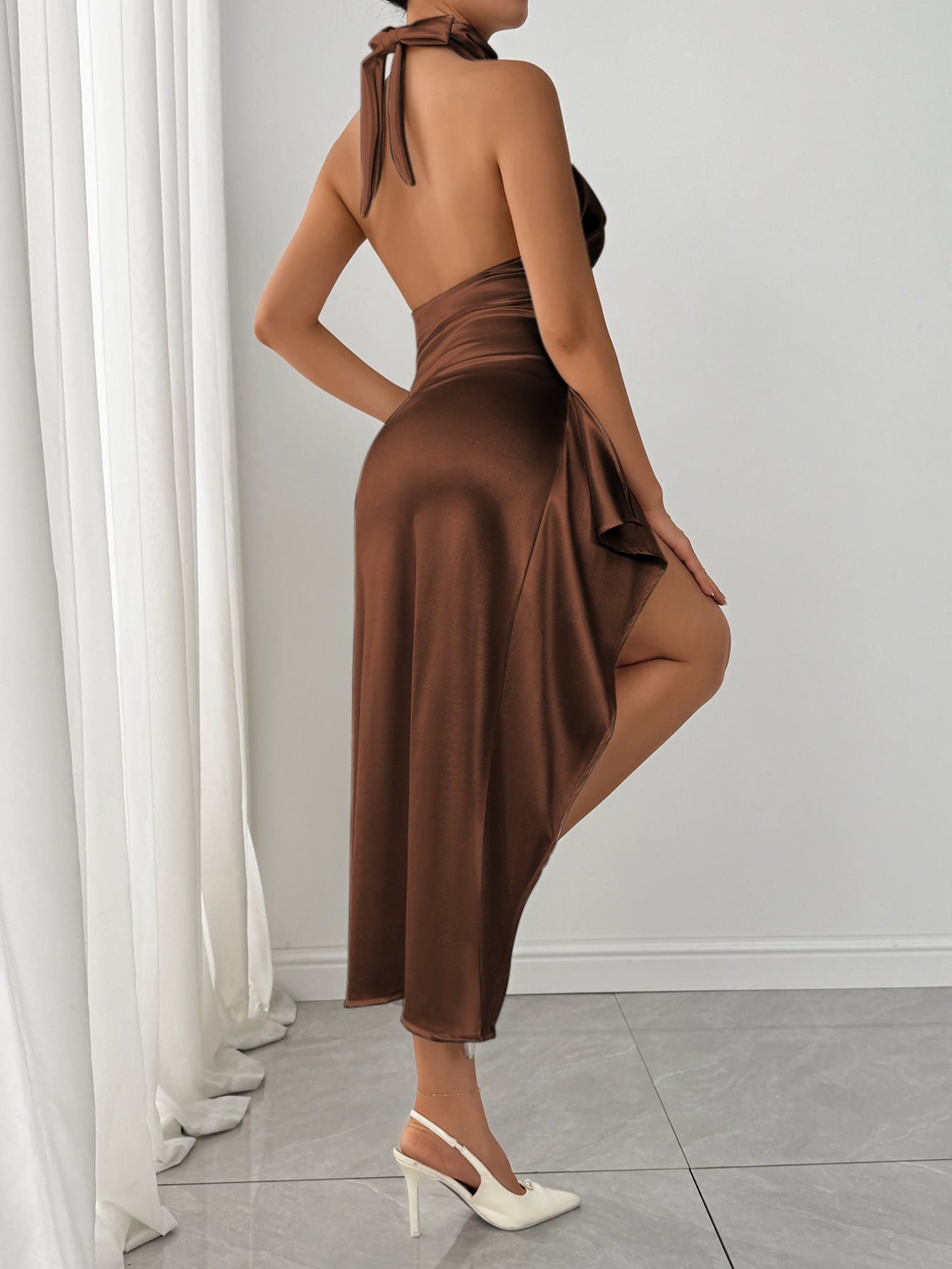 Brown satin halter dress with a thigh-high slit and tie back detail.