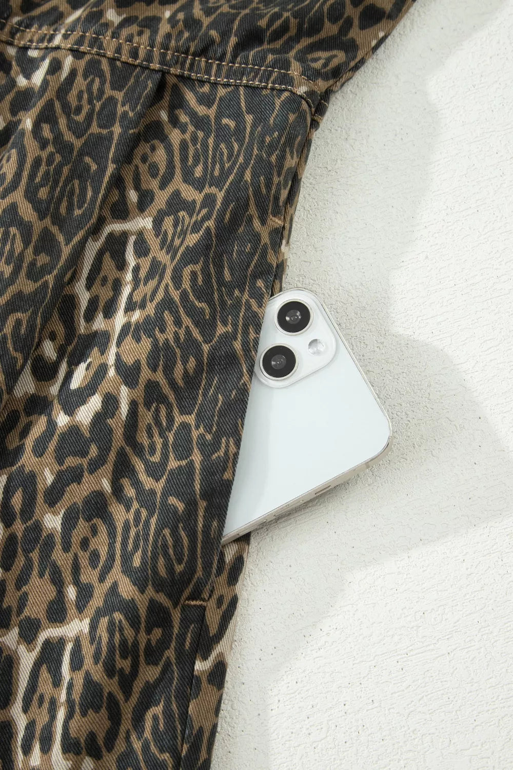 Leopard print denim dress with a pocket holding a smartphone