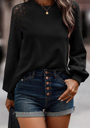 Black waffle knit raglan top with lace yoke detail and long sleeves.