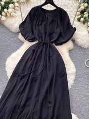 Black floral maxi dress with puff sleeves, tie waist, and button front.