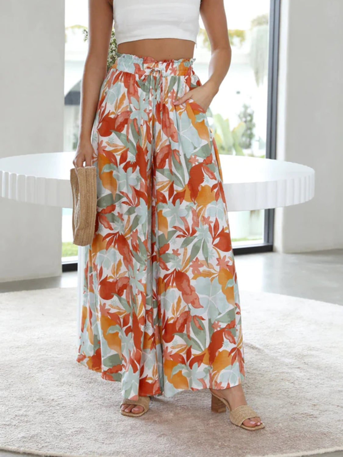 Palazzo trousers with a watercolor floral print in orange and green, featuring a drawstring waist and wide legs.