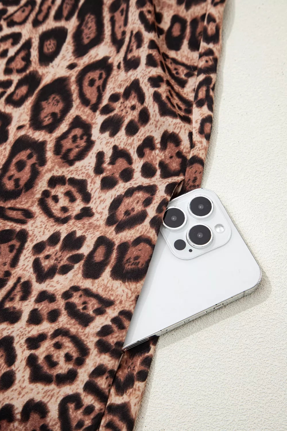 Leopard print cotton mini dress with a pocket shown holding a smartphone.