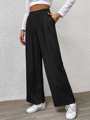 Black wide leg trousers with front pleats and pockets, styled casually.