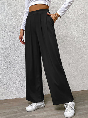 Black wide leg trousers with front pleats and pockets, styled casually.