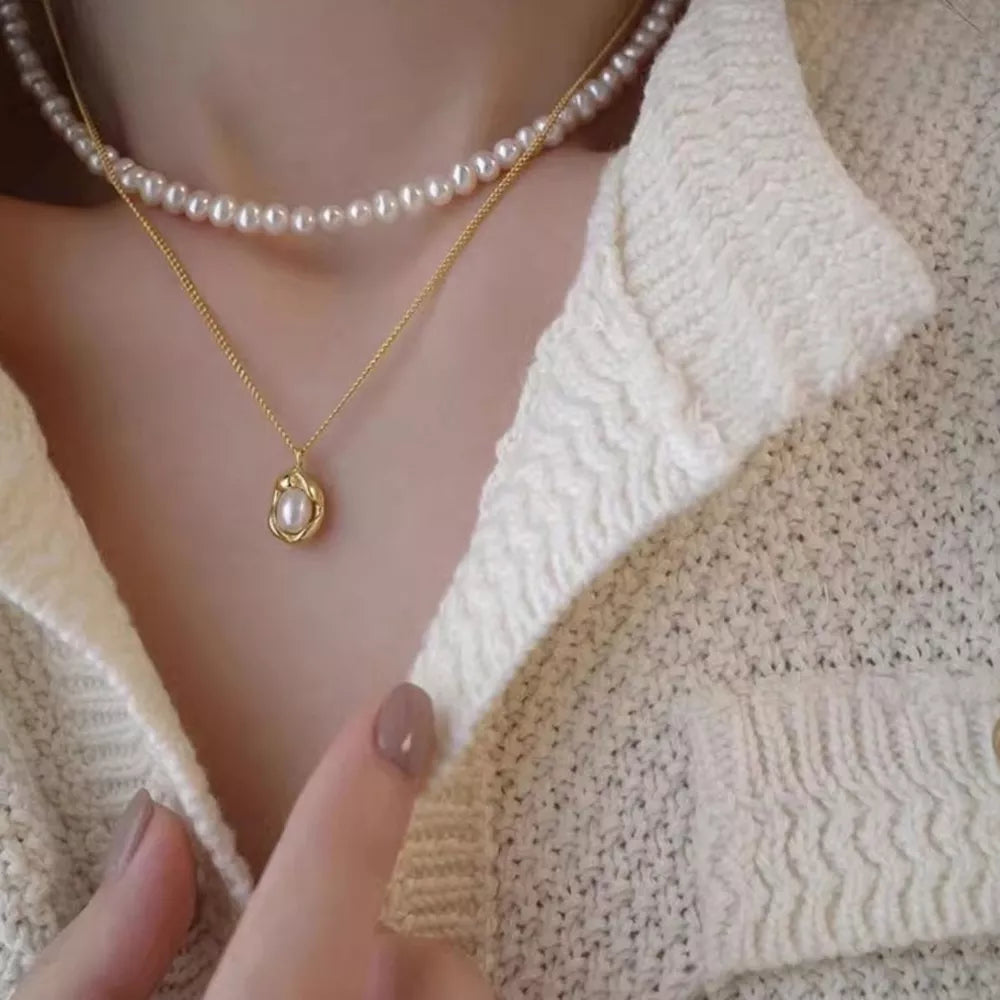 Gold pearl pendant necklace layered with a freshwater pearl strand necklace.