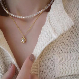 Gold pearl pendant necklace layered with a freshwater pearl strand necklace.