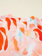 Vibrant abstract print mini dress with a round neckline and short sleeves, featuring a watercolor-style pattern in orange