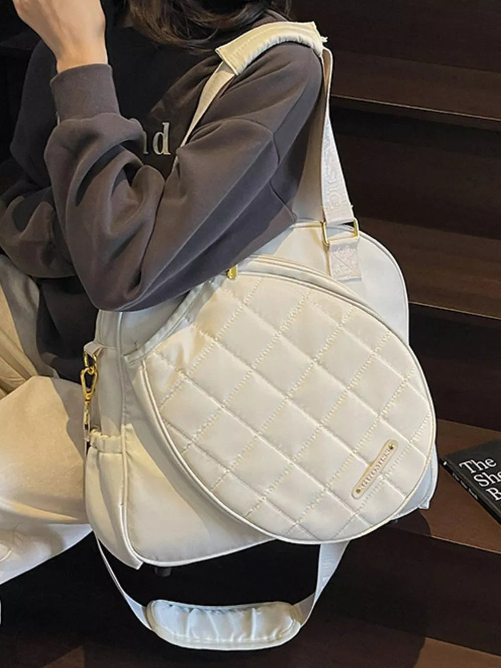Quilted off-white Oxford bag with adjustable strap and racket compartment.