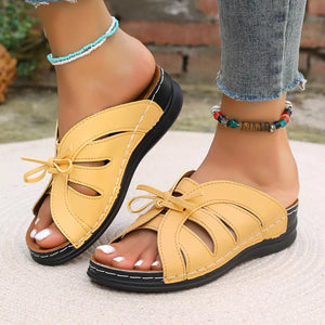 Yellow criss-cross wedge sandals with bow detail and open toe.