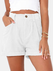 White corduroy pleated high-waist shorts with button closure and cuffed hem.