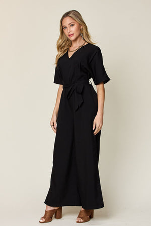 Black wrap jumpsuit with V-neck, short sleeves, and wide slit legs.