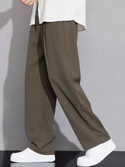 Men's brown wide-leg chinos with a relaxed fit, styled with a white shirt and sneakers.
