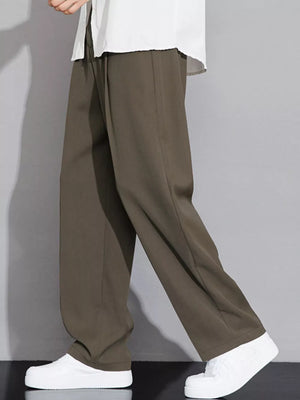 Men's brown wide-leg chinos with a relaxed fit, styled with a white shirt and sneakers.