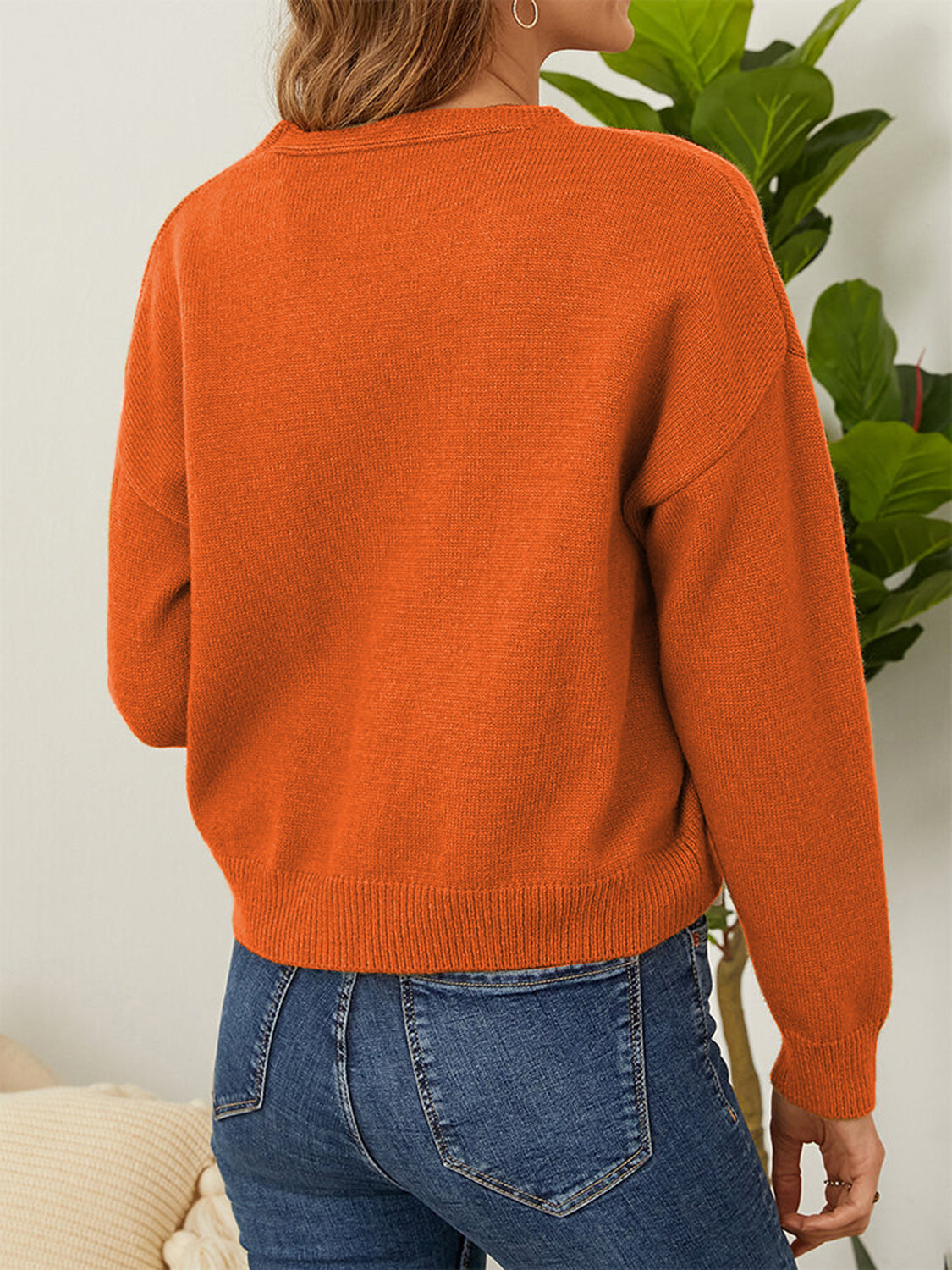 Orange V-neck cardigan with ribbed cuffs and hem, detailed view from back.