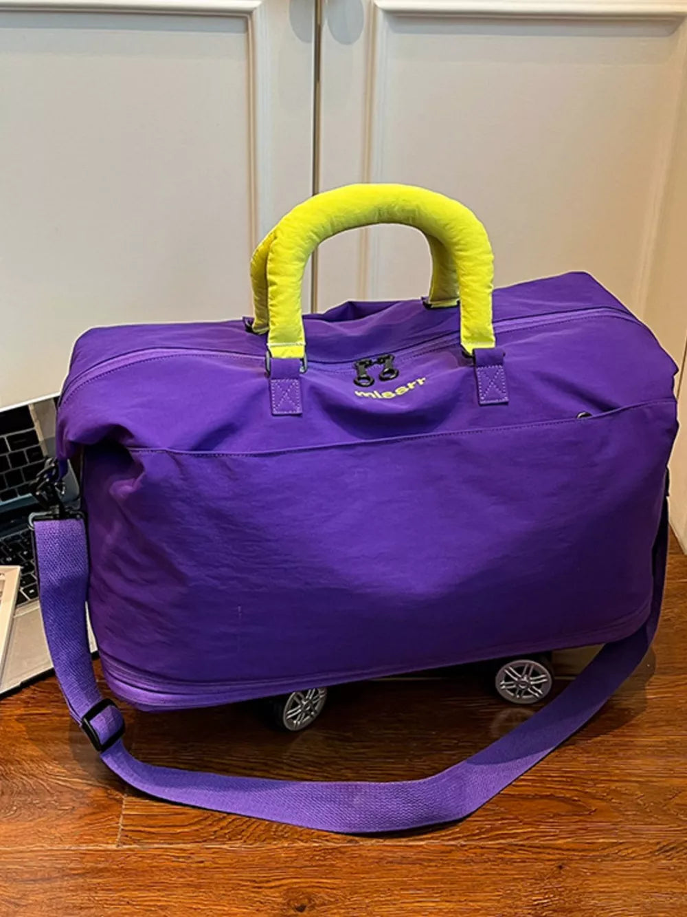 Vibrant purple travel bag with neon yellow handles and shoulder strap.