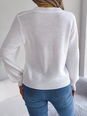White ribbed yoke knit sweater with textured sleeves and crew neck, styled with jeans.