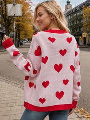 Blush pink acrylic cardigan with red intarsia hearts and trim.